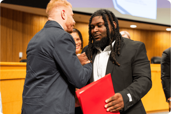 A graduate shaking hands with a mentor